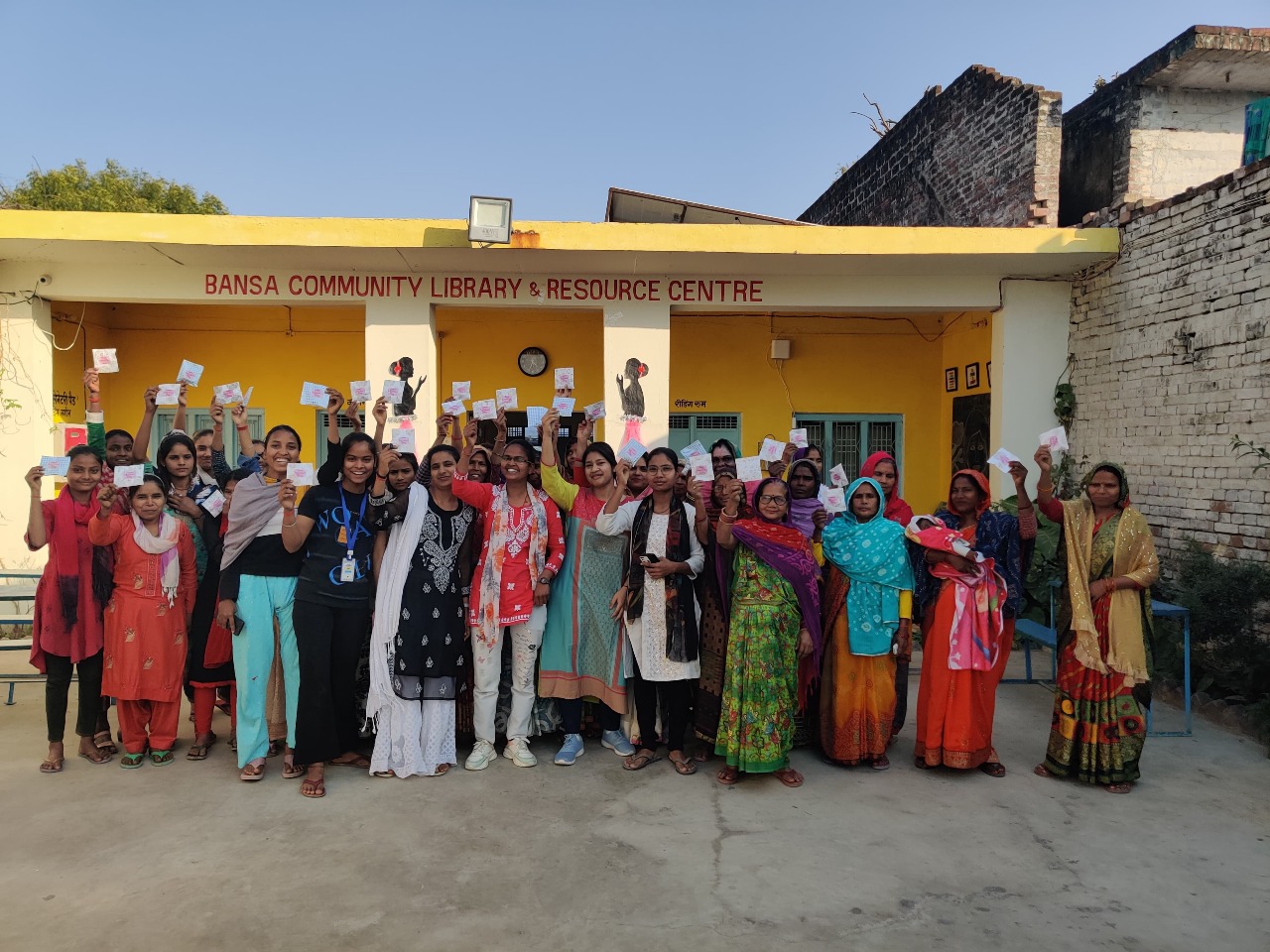 Community members holding up papers in front of Bansa Community Library