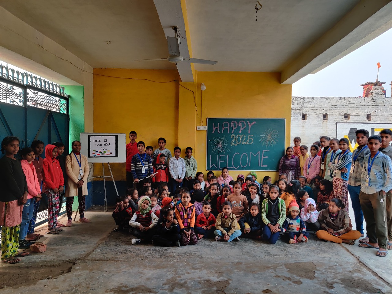 Children gathered in an outdoor learning space with a blackboard